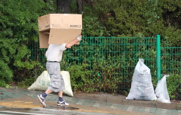 지난 6일 서울시 중랑구에서 갑자기 내린 소나기에 종이상자를 덮고 비를 피하는 시민. ⓒ뉴시스