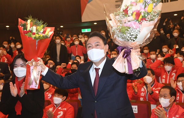 20대 대통령으로 선출된 윤석열 당선인이 꽃을 든 두 손을 번쩍 들어올리며 국민의힘 당원들과 지지자들의 환호에 답하고 있다.ⓒ뉴시스